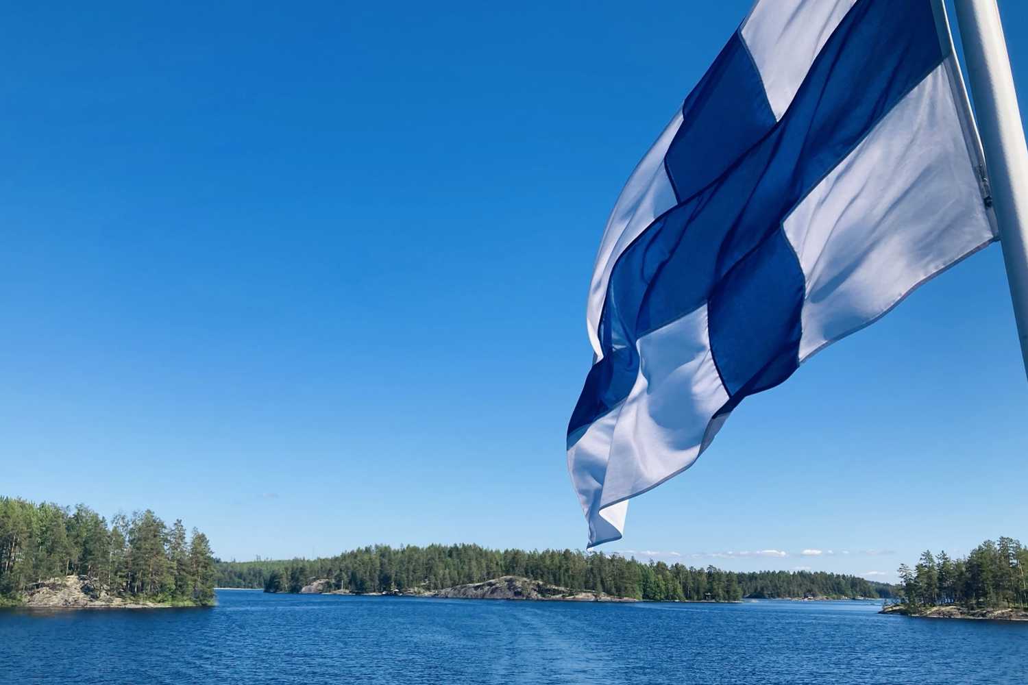 Finlands flagga i förgrund och skärgård i bakgrund